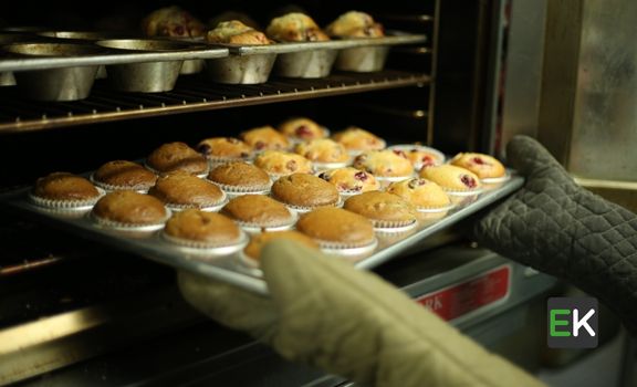 Women putting cupcakes in oven